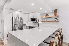A modern kitchen with white cabinetry, stainless steel appliances, and a central island. - Playa Kas Waterfront Townhouse (Indian Rocks Beach)