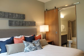 A hotel room with a bed, pillows, a nightstand, a lamp, and a sliding door to the bathroom. - Ski-in/out suite at Grand Colorado Peak 8, pools, spa, sleeps 4 (Breckenridge)