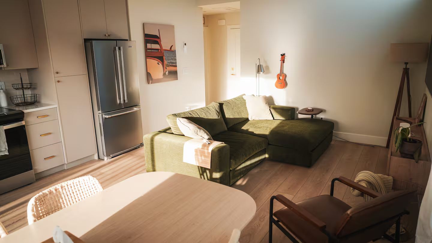 Un espacio habitable moderno con cocina, comedor y zona de estar con sofá y sillones.