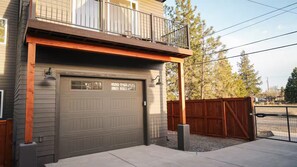 A two-story house with a garage door, a balcony, and a wooden fence. - Bend river park retreat (Bend)