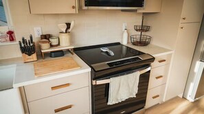 A modern kitchen with a black induction cooktop, white cabinets, and a stainless steel refrigerator. - Bend river park retreat (Bend)