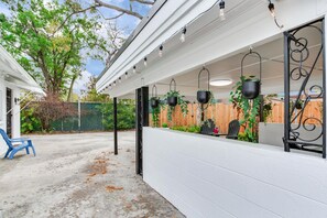 An outdoor patio with a white wall, hanging planters, and a blue chair. - Cozy 2-bedroom house in charming Tampa with AC (Tampa)
