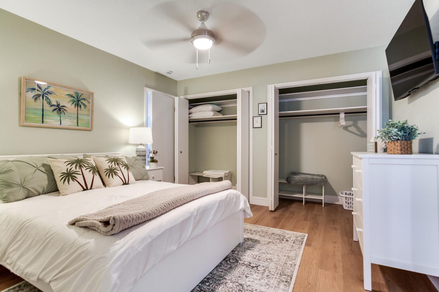A bedroom with a bed, a bedside table, a lamp, a closet, and a television.