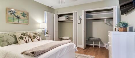 A bedroom with a bed, a bedside table, a lamp, a closet, and a television.