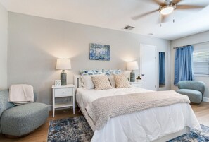 A bedroom with a bed, nightstands, a chair, a ceiling fan, and a window with curtains. - Cozy 2-bedroom house in charming Tampa with AC (Tampa)
