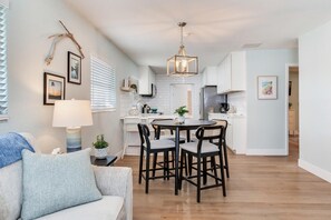 A modern kitchen with white cabinets, a dining table with chairs, and a pendant light. - Cozy 2-bedroom house in charming Tampa with AC (Tampa)