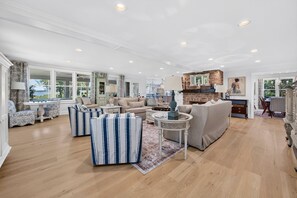 A spacious living room with a fireplace, a dining area, and a view of the outdoors. - Winyah Bay A Luxury Waterfront Estate with Guest House and Pool (Georgetown)