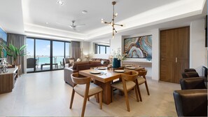 A modern living room with a dining area, large windows, and a view of the sea. - Two 501: Beachfront Paradise | Sonoran Star Resort (Puerto Peñasco)