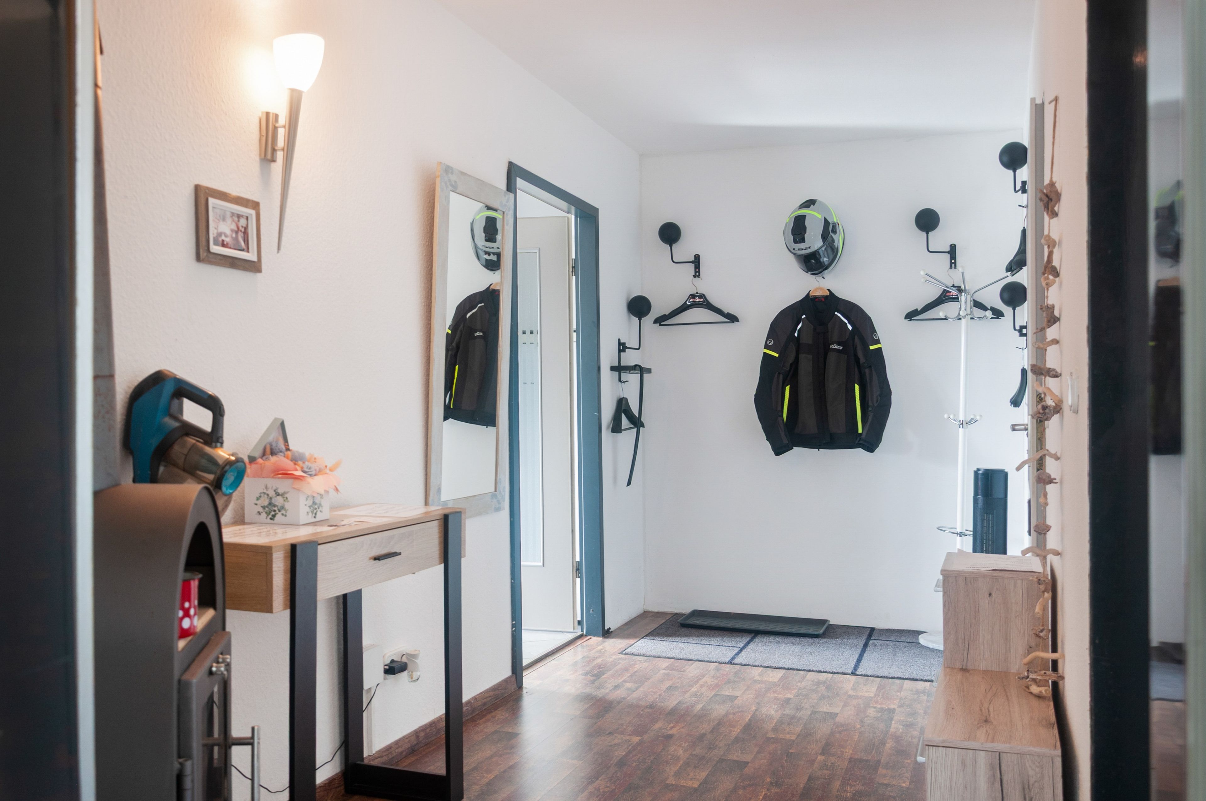 Ein Zimmer mit einem Holztisch, einem Spiegel, einem am Wand befestigten Fahrradständer und einer Tür.