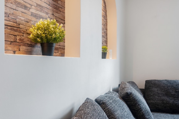 A modern interior with a stone wall, a potted plant, and grey upholstered seating.