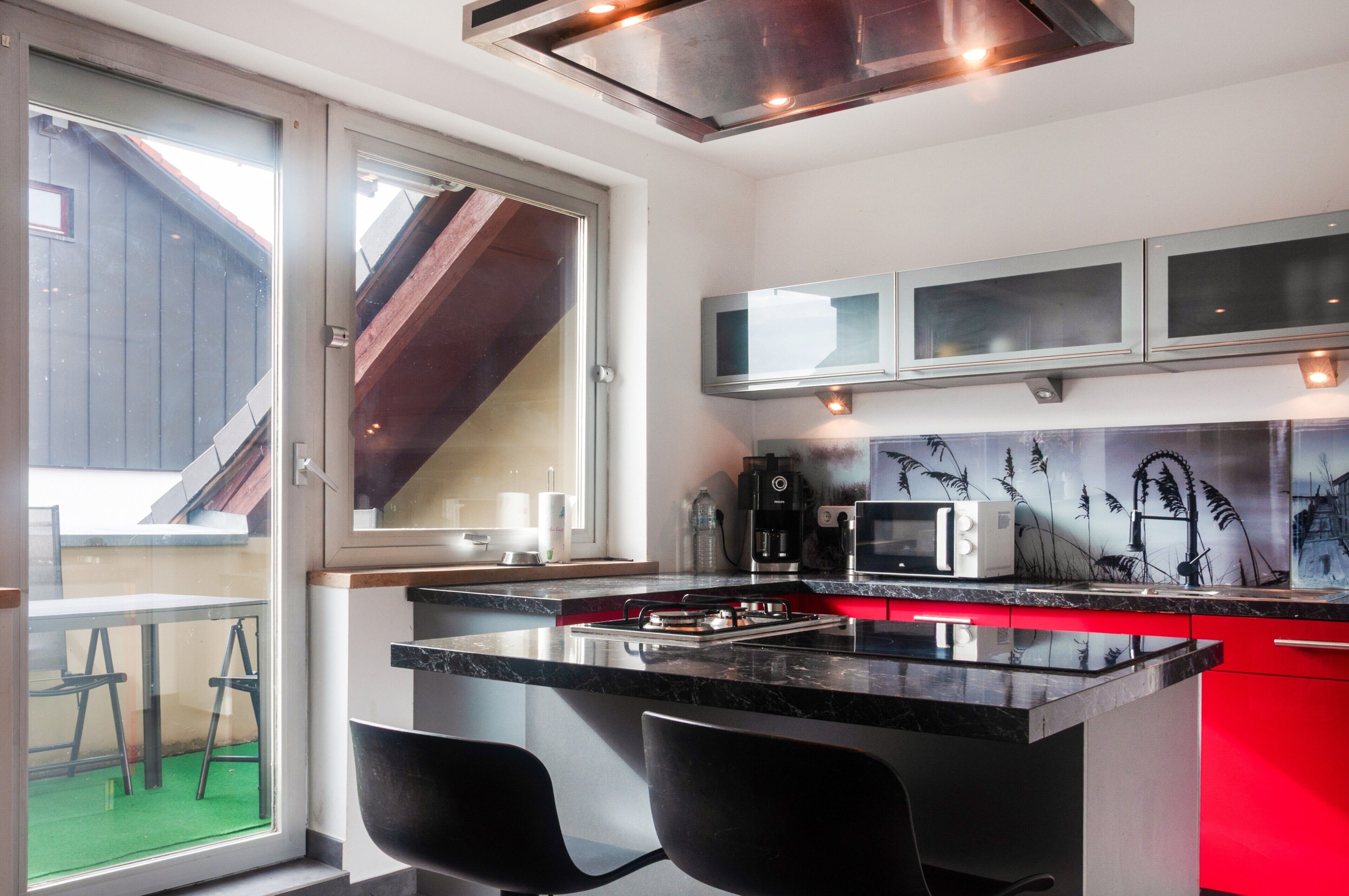 A modern kitchen with a central island, bar stools, a microwave, and a coffee maker.