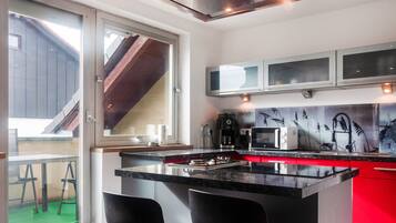 A modern kitchen with a central island, bar stools, a microwave, and a coffee maker.