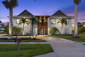 A modern two-story house with a symmetrical facade, large windows, and a central entrance. - Island Living, Perfected — Southern Island Retreat w/Pool and Dock; Close to Beach & Hotspots. (Marco Island)