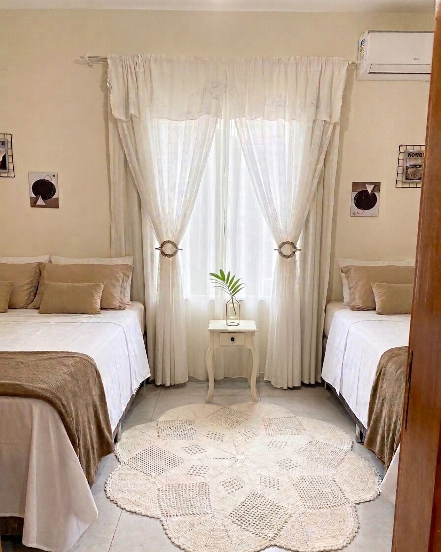 Ein Schlafzimmer mit zwei Betten, einem kleinen Nachttisch mit einer Pflanze und einem dekorativen Teppich.