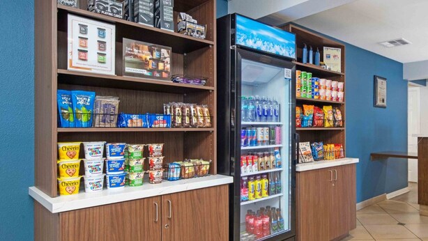 A snack bar with shelves stocked with various snacks and beverages, a refrigerator, and a counter with a coffee machine.