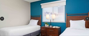 A bedroom with two single beds, a nightstand with a lamp, and a window with blinds. - Spencer St. Resort - Spacious  2BDR - SLEEPS 6 - Full Kitchen – Jan. 3–10, 2027 (Las Vegas)