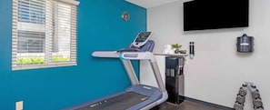 A room with a treadmill, a water dispenser, and a TV mounted on the wall. - CES 2027 LAS VEGAS  Resort  1BDR - Sleeps 4 - Full Kitchen – JANUARY 5–10, 2027 (Las Vegas)