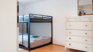A bedroom with a bunk bed, a dresser with drawers, and a mirror on the wall.
