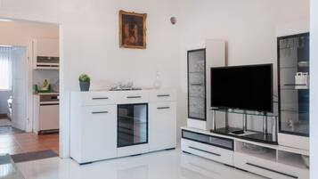 A modern kitchen with white cabinetry, a built-in oven, and a glass-fronted wine cabinet.