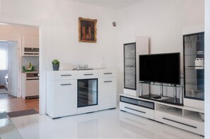 Une cuisine moderne avec des meubles blancs, un four encastré et un meuble à vin avec une porte en verre.