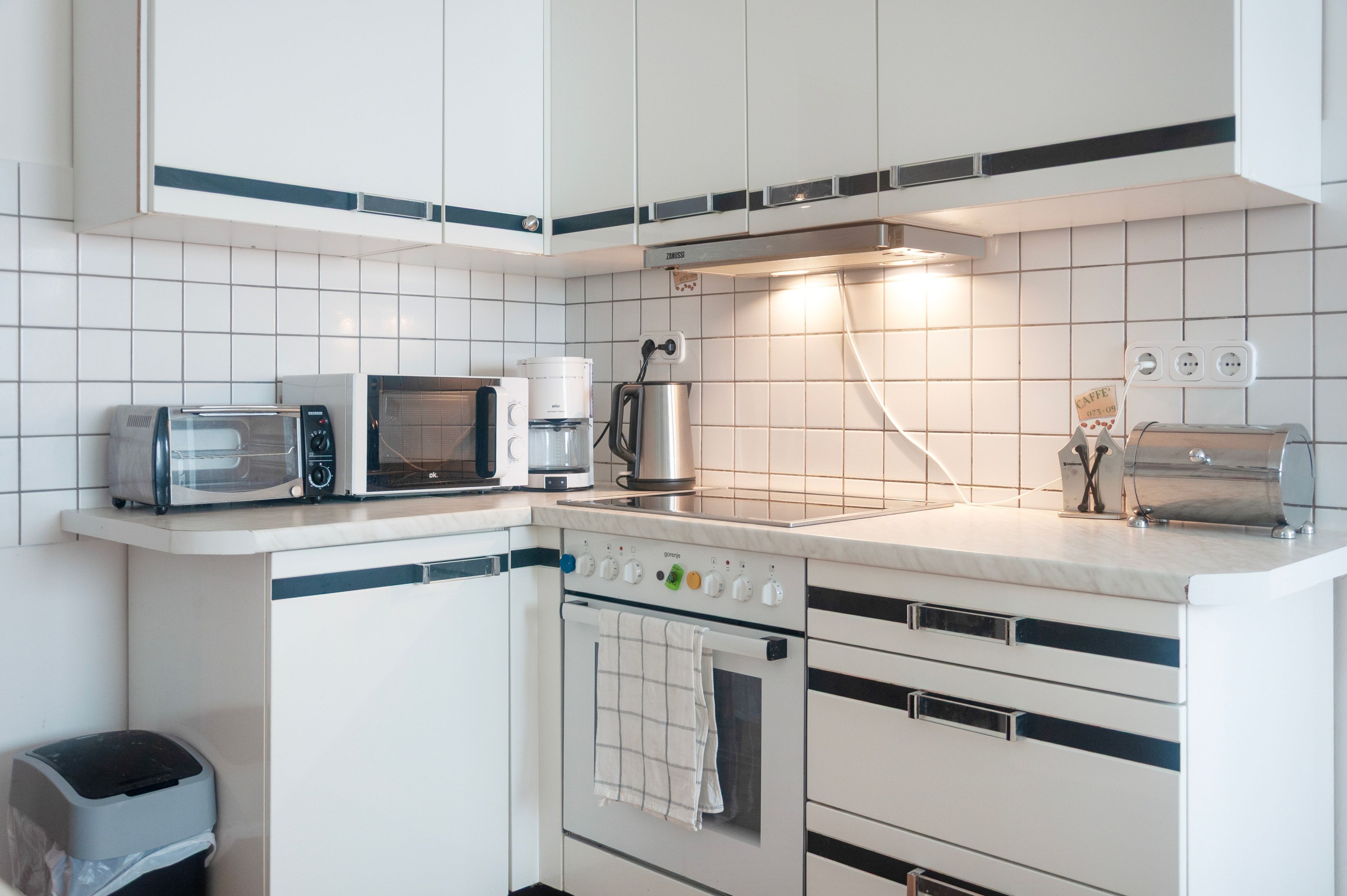 A kitchen with white cabinets, a microwave, a coffee maker, and a toaster.
