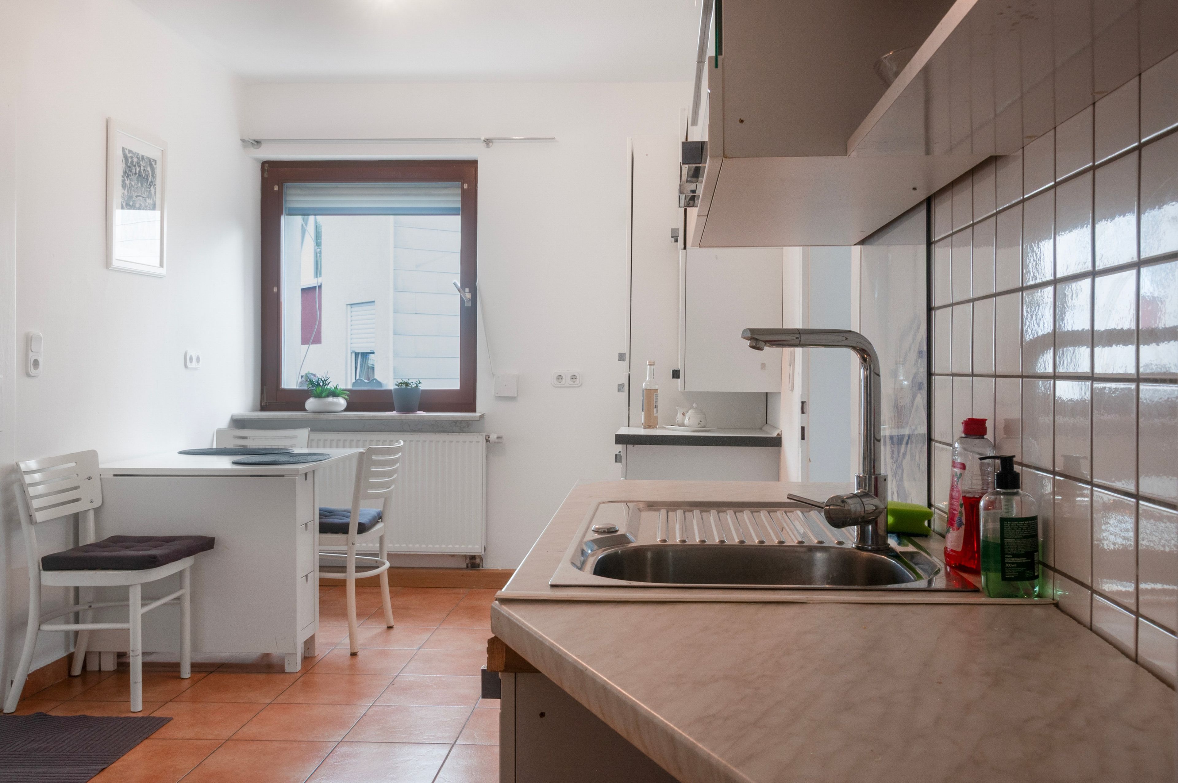 Cocina compacta con pileta, mostrador y ventana con persianas.