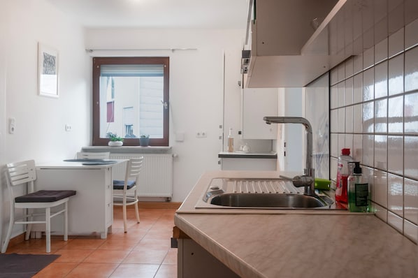 A compact kitchen with a sink, countertop, and a window with blinds.