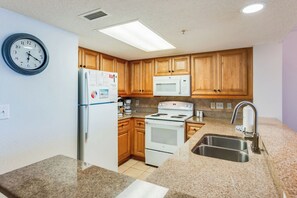 A kitchen with wooden cabinets, a refrigerator, a microwave, a stove, and a sink. - Coastal Paradise Feels with Breathtaking Views (Myrtle Beach)