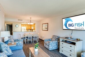 A furnished living room with a dining area, a kitchenette, and a TV displaying 'BIG FISH Rentals'. - Coastal Paradise Feels with Breathtaking Views (Myrtle Beach)