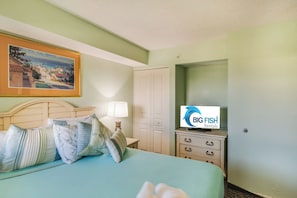 A hotel room with a bed, pillows, a nightstand, a lamp, a dresser, a television, and a painting on the wall. - Coastal Paradise Feels with Breathtaking Views (Myrtle Beach)