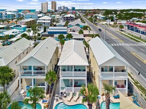 Um hotel na praia com edifícios de vários andares, uma piscina e uma estrada ao fundo.