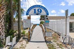 Une entrée de plage avec un panneau indiquant l’accès public à la plage du comté de Bay, un panneau d’avertissement et un panneau indiquant « Ne laissez aucune trace de votre passage ».