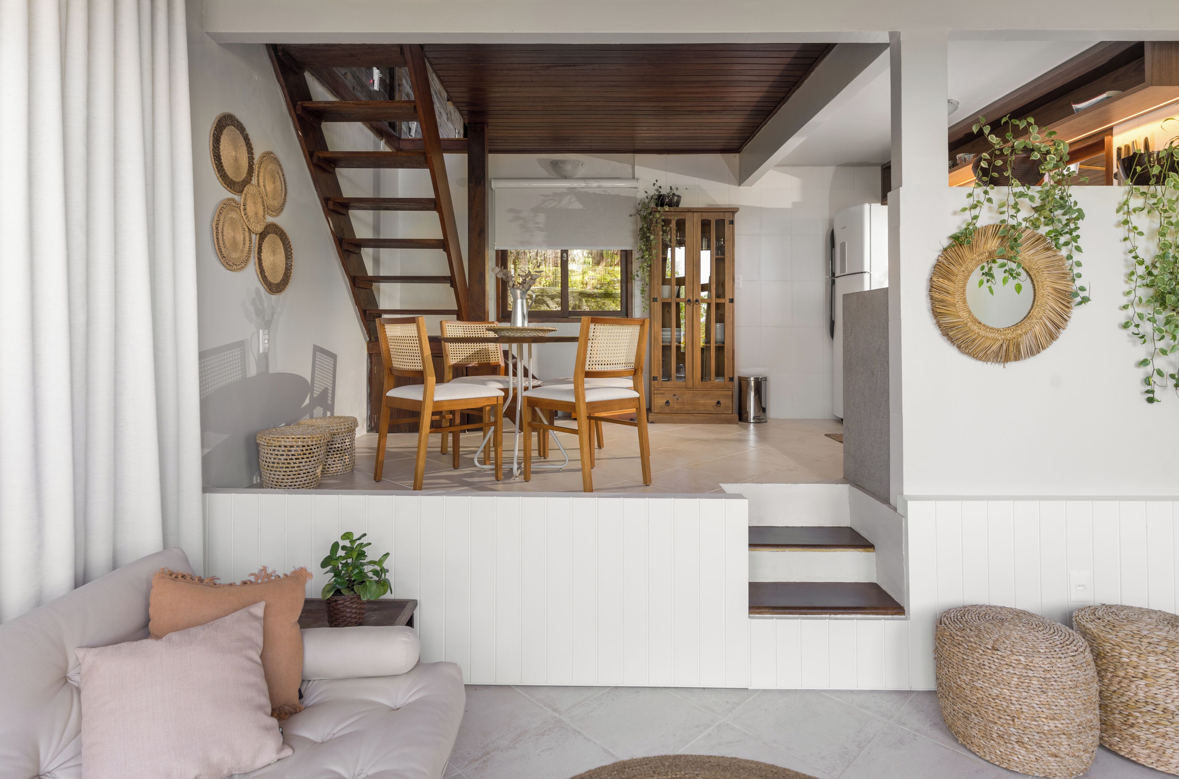 A modern interior with a dining area, staircase, and a living room with a sofa and cushions.