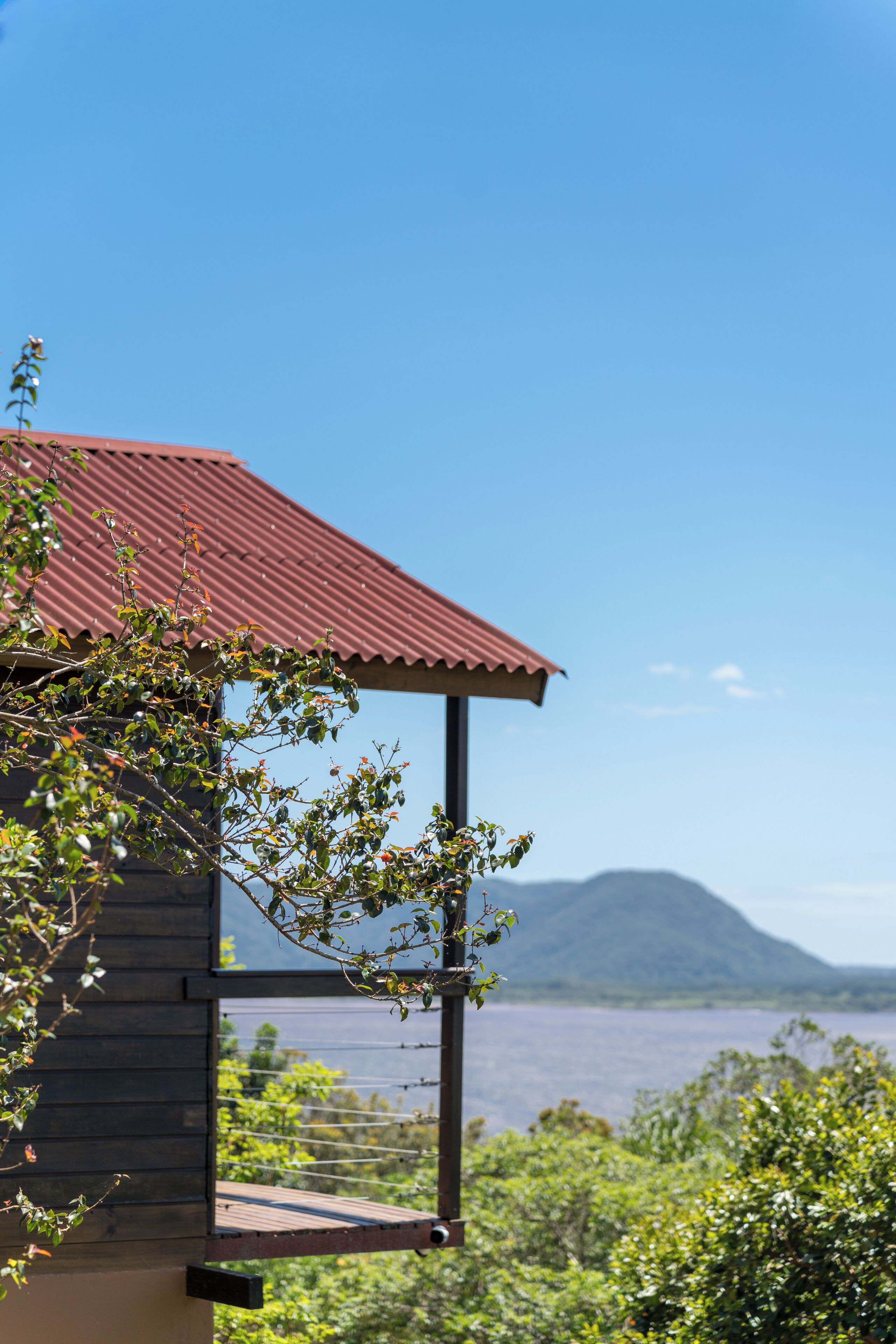 Uma cabana de madeira com telhado vermelho, com vista para um corpo de água e uma montanha.
