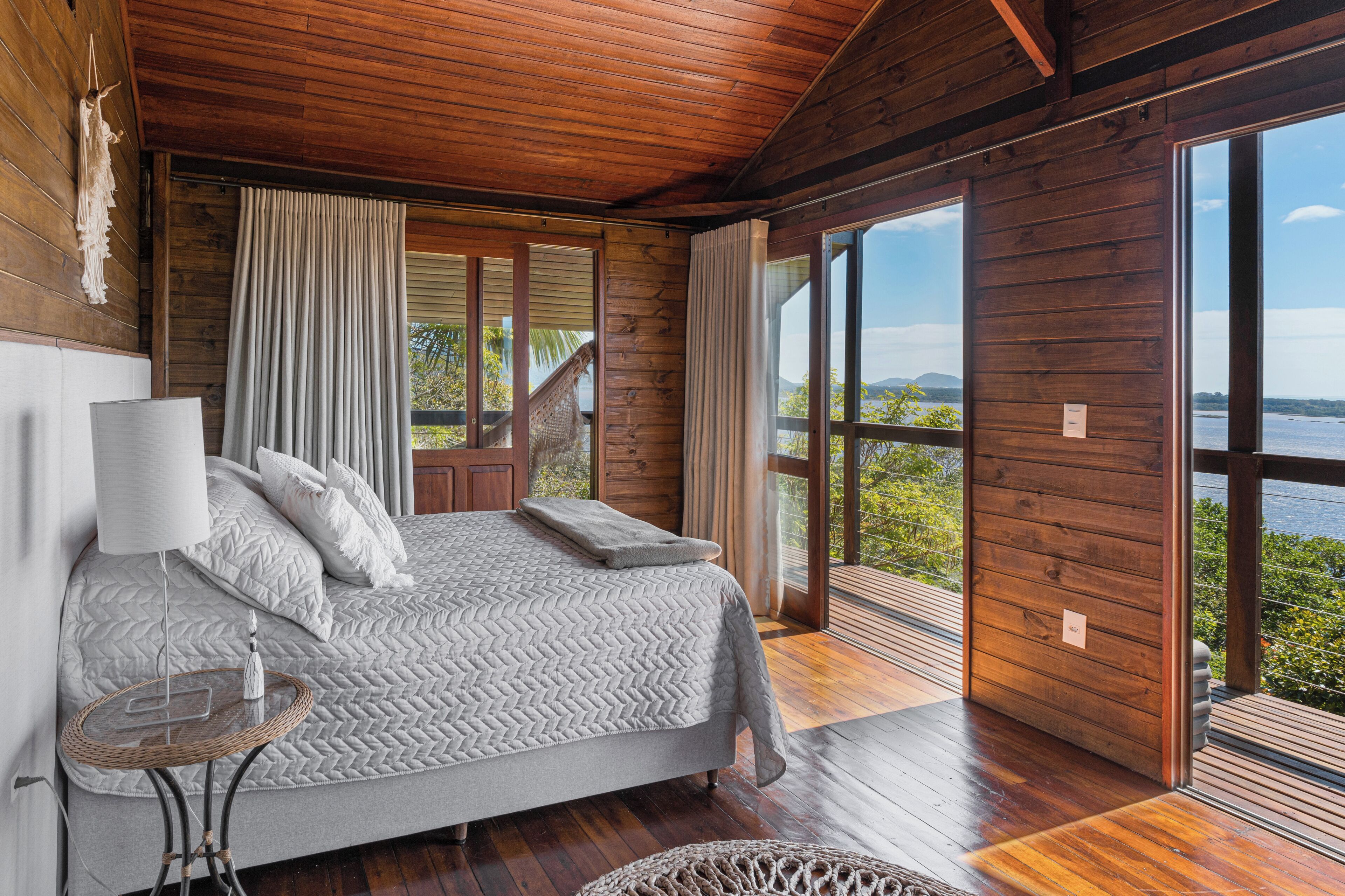 Une chambre avec un grand lit, des murs en bois et une vue sur l’extérieur.