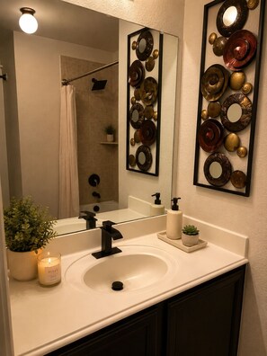 A bathroom with a white sink, black faucet, a mirror, and decorative wall art. - Perfect 4-bedroom house with AC in fabulous Anna Tx (Anna Tx)