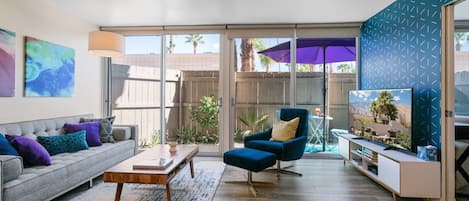 A living room with a sofa, coffee table, blue armchair, and TV.