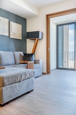 A modern living room with a grey sofa, a wooden side table, and a floor lamp. - Casa Amazcala by Cosmos Homes (Zibatá)