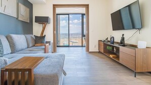 Un salon moderne avec un canapé, une table basse, un téléviseur et une porte-fenêtre donnant sur un balcon.