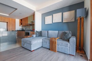 Ein modernes Wohnzimmer mit einem grauen Ecksofa, Holznachttischen und einer Stehlampe.