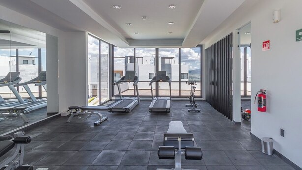 Una palestra con tapis roulant, una panca per pesi e un estintore a parete.