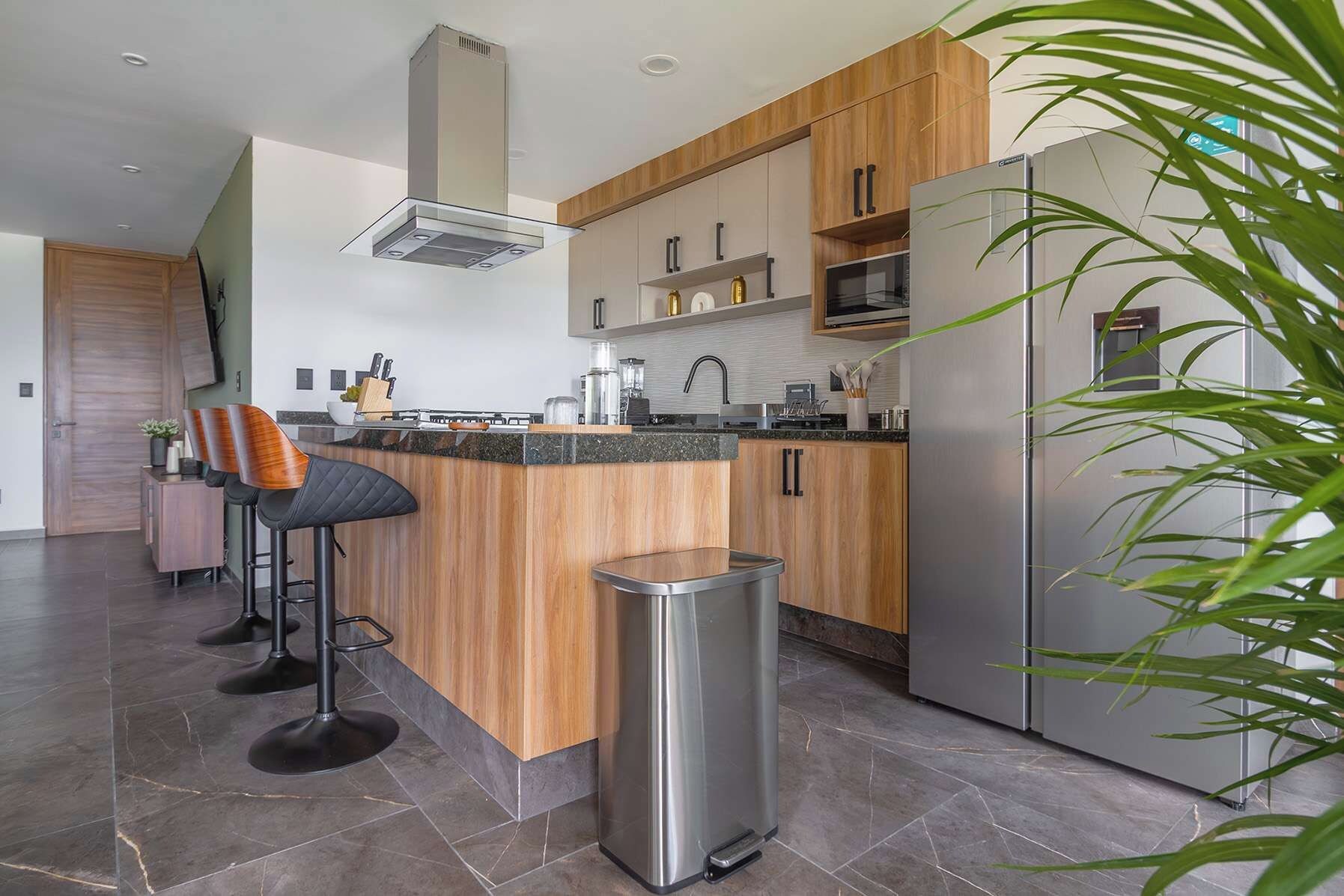 Una cocina moderna con una isla central, electrodomésticos de acero inoxidable y armarios de madera.