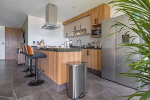 Una cocina moderna con una isla central, electrodomésticos de acero inoxidable y armarios de madera.