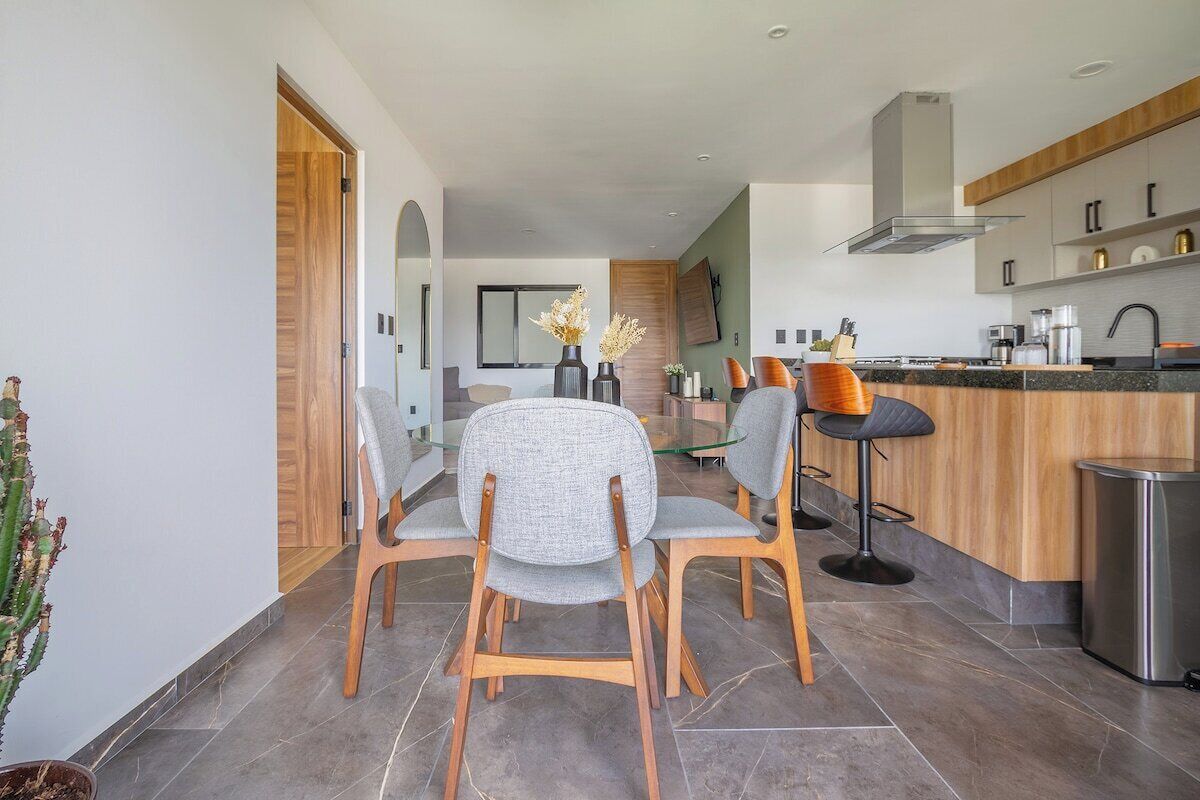 Een moderne keuken met een centraal eiland, houten stoelen en een eethoek met een glazen tafel.