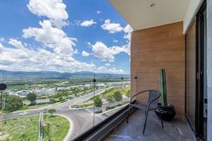 Un balcón con vista a un paisaje urbano, un cactus y una silla.