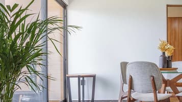 A modern dining area with a large window, a potted plant, and a table with chairs.