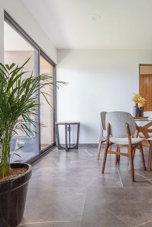 Un espace repas moderne avec une grande fenêtre, une plante en pot et une table avec des chaises.