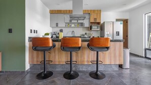 Una cucina moderna con tre sgabelli da bar, un forno a microonde e un frigorifero.
