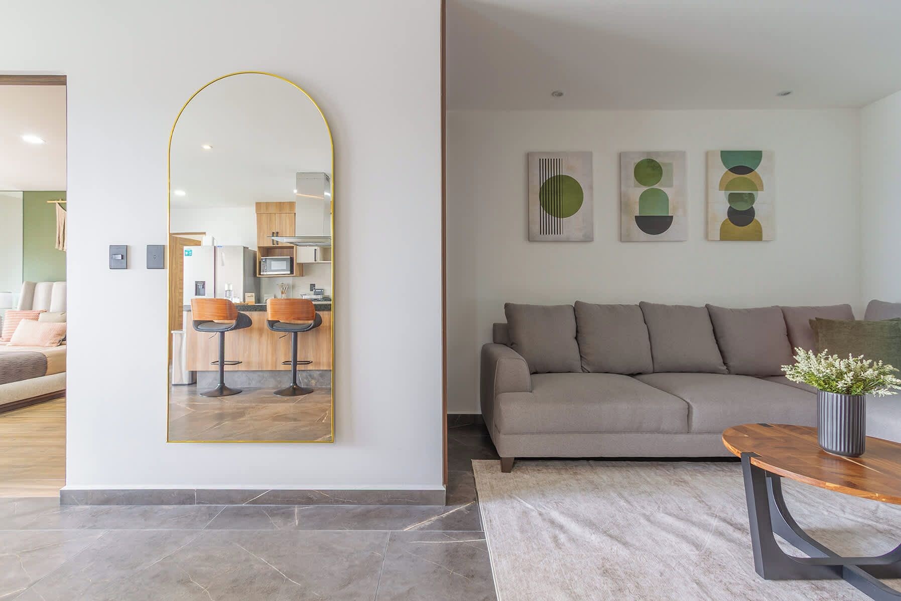 A modern living room with a large mirror, a sofa, a coffee table, and abstract wall art.