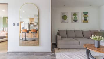 Een moderne woonkamer met een grote spiegel, een bank, een salontafel en abstracte wanddecoratie.